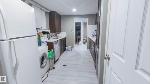 Galley kitchen featuring wood-finish cabinetry, light-toned countertops, and a white subway tile backsplash - 3311 108 Street, Edmonton, AB - Indoor Photo Showing Other Room