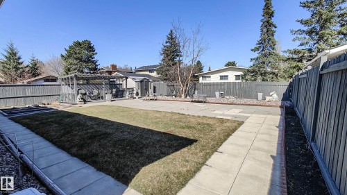 Expansive backyard featuring a central lawn, perimeter fencing, and concrete pathways - 3311 108 Street, Edmonton, AB - Outdoor