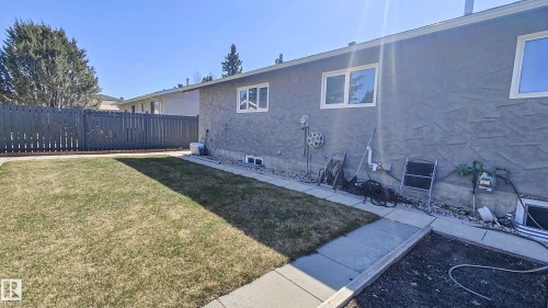 Private backyard featuring a gray picket fence, mature landscaping, and a manicured lawn - 3311 108 Street, Edmonton, AB - Outdoor