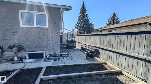 Exterior showcasing textured stucco siding, white-framed windows, and a basement window well - 3311 108 Street, Edmonton, AB - Outdoor
