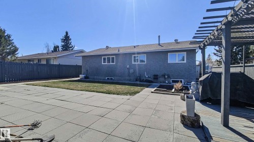 Expansive rear yard featuring a large paver patio, a wooden deck with a pergola, and a manicured lawn area - 3311 108 Street, Edmonton, AB - Outdoor