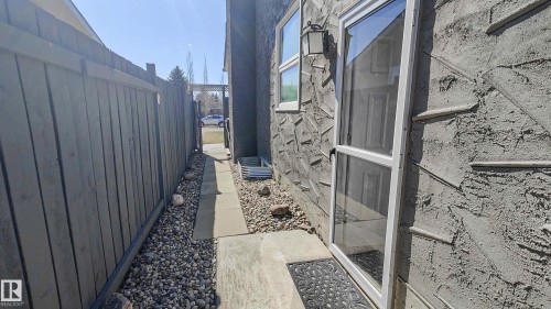Textured exterior wall with a white-framed glass door and a window - 3311 108 Street, Edmonton, AB - Outdoor