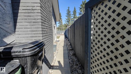 Side path featuring a concrete walkway, gravel landscaping, and a wood privacy fence with decorative lattice - 3311 108 Street, Edmonton, AB - Outdoor