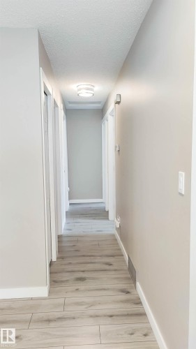 Corridor with wood-finish flooring, light neutral wall paint, white trim, and a modern flush-mount ceiling fixture - 3311 108 Street, Edmonton, AB - Indoor Photo Showing Other Room