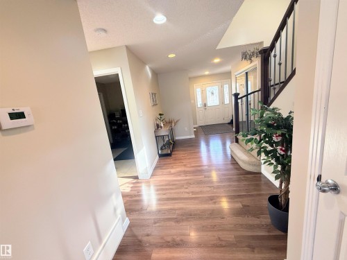 Inviting entryway featuring wood-finish flooring, a staircase with dark wood banister and wrought iron spindles, and recessed ceiling lighting - 3538 Claxton Crescent, Edmonton, AB - Indoor Photo Showing Other Room