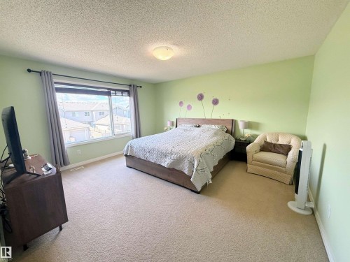 Carpeted room with a wide window, light green walls, and a textured ceiling - 3538 Claxton Crescent, Edmonton, AB - Indoor Photo Showing Bedroom