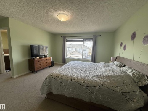 Carpeted bedroom with a single window, light green walls, and ceiling-mounted dome light fixture - 3538 Claxton Crescent, Edmonton, AB - Indoor Photo Showing Bedroom