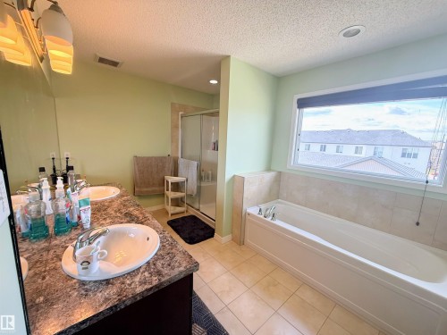 Bathroom featuring a dual vanity with undermount sinks, a built-in soaking tub, a stand-up glass-enclosed shower, and a large window - 3538 Claxton Crescent, Edmonton, AB - Indoor Photo Showing Bathroom