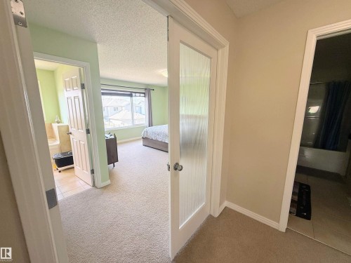 Carpeted hallway with light-colored walls, featuring a white interior door with a frosted glass panel - 3538 Claxton Crescent, Edmonton, AB - Indoor Photo Showing Other Room