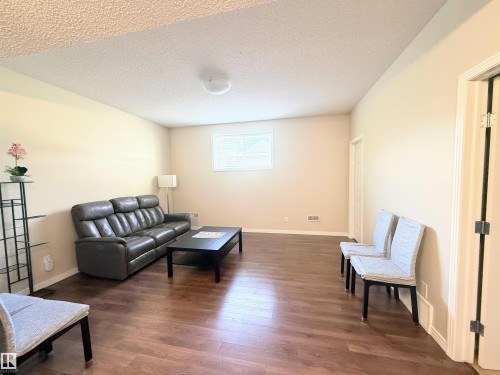 Spacious room featuring wood-finish flooring, a white trim window, and light-colored walls - 3538 Claxton Crescent, Edmonton, AB - Indoor Photo Showing Living Room