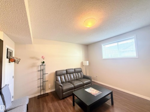 Spacious room featuring wood-finish flooring, a contemporary window with blinds, and a neutral wall color - 3538 Claxton Crescent, Edmonton, AB - Indoor Photo Showing Living Room