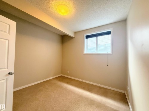 Carpeted room featuring a window with blinds, beige walls, white trim, and a ceiling-mounted light fixture - 3538 Claxton Crescent, Edmonton, AB - Indoor Photo Showing Other Room