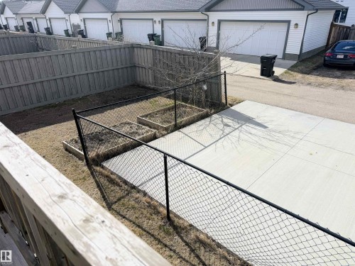 Fenced backyard featuring a concrete patio, two raised garden beds, and a wood privacy fence - 3538 Claxton Crescent, Edmonton, AB - Outdoor With Exterior