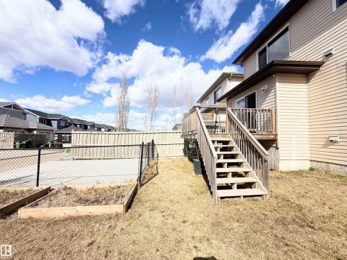 Rear exterior featuring a wood deck with stairs, beige vinyl siding, and a sliding glass door - 3538 Claxton Crescent, Edmonton, AB - Outdoor With Exterior