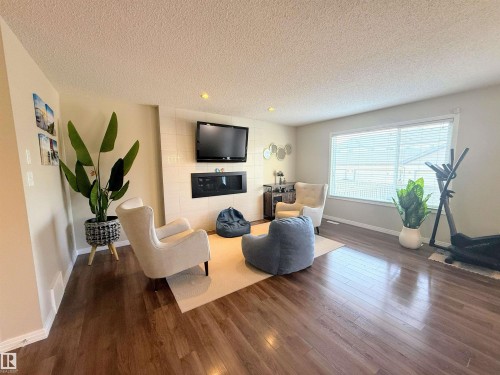 Spacious living area featuring wood-finish flooring, recessed lighting, and a modern built-in fireplace - 3538 Claxton Crescent, Edmonton, AB - Indoor Photo Showing Living Room With Fireplace