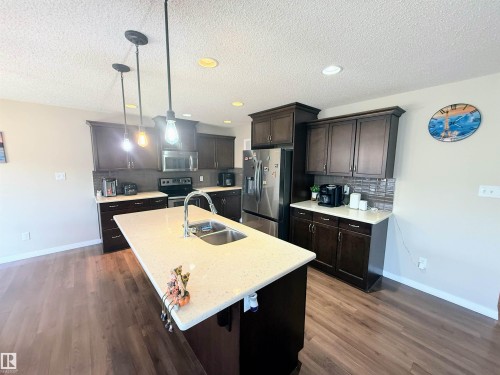 Central kitchen island with an undermount double basin sink and gooseneck faucet - 3538 Claxton Crescent, Edmonton, AB - Indoor Photo Showing Kitchen With Stainless Steel Kitchen With Double Sink With Upgraded Kitchen
