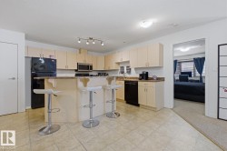 Kitchen featuring light wood-finish cabinetry, black appliances, a stone-finish countertop, and a breakfast bar - 