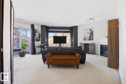 Carpeted living space featuring a built-in fireplace, track lighting, and outdoor balcony access through sliding glass doors - 