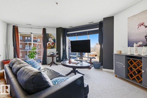 Living area featuring light-colored carpeting and white walls with contrasting dark accent walls - 304 4312 139 Ave, Edmonton, AB - Indoor