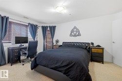Carpeted bedroom featuring a window with horizontal blinds, a ceiling-mounted light fixture, and a solid white door - 