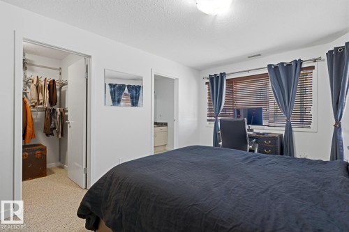 Bedroom featuring neutral wall paint, textured carpeting, and a window with wood-finish blinds - 304 4312 139 Ave, Edmonton, AB - Indoor Photo Showing Bedroom