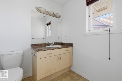 Bathroom featuring a single vanity with light wood-finish cabinetry, a white basin, and a speckled countertop - 304 4312 139 Ave, Edmonton, AB - Indoor Photo Showing Bathroom