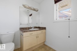 Bathroom featuring a single vanity with light wood-finish cabinetry, a white basin, and a speckled countertop - 
