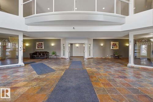 Two-story foyer featuring multi-toned tile flooring, recessed lighting, and a second-story balcony with a glass railing - 304 4312 139 Ave, Edmonton, AB - Indoor Photo Showing Other Room