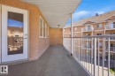 Spacious balcony featuring a textured wall finish, white metal railings, multiple windows, and a full-light entry door - 304 4312 139 Ave, Edmonton, AB  - Outdoor With Balcony With Exterior 