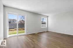 Spacious room with wood-finish flooring, light grey painted walls, and a textured white ceiling - 