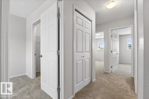 Hallway featuring light-colored carpeting, white paneled doors, and neutral wall paint - #7 18004 89 St Nw, Edmonton, AB - Indoor Photo Showing Other Room
