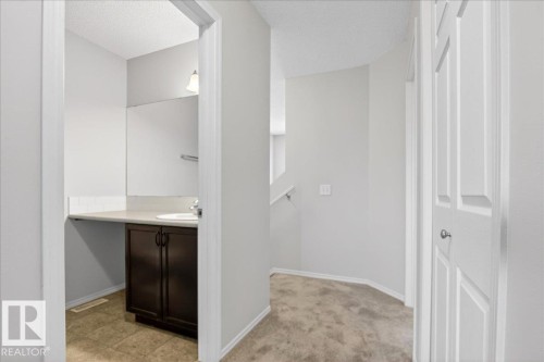 Hallway with neutral carpeting and white painted walls, featuring a bathroom entrance - #7 18004 89 St Nw, Edmonton, AB - Indoor Photo Showing Other Room