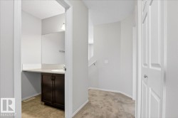 Hallway with neutral carpeting and white painted walls, featuring a bathroom entrance - 