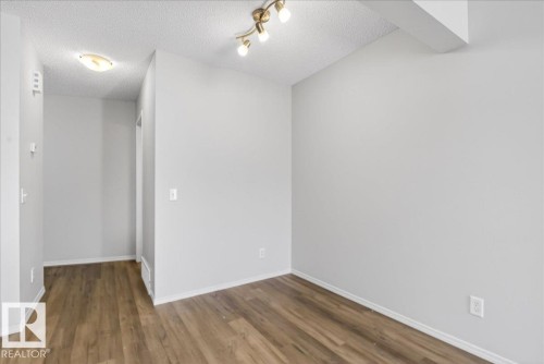 Open-concept interior featuring wood-finish flooring, light gray wall paint, and white baseboards - #7 18004 89 St Nw, Edmonton, AB - Indoor Photo Showing Other Room