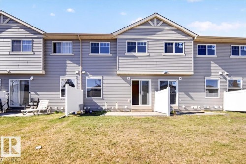 Rear exterior featuring light grey horizontal siding, multiple upper-level windows, and a lower-level sliding glass door - #7 18004 89 St Nw, Edmonton, AB - Outdoor