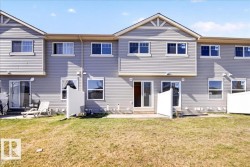 Rear exterior featuring light grey horizontal siding, multiple upper-level windows, and a lower-level sliding glass door - 
