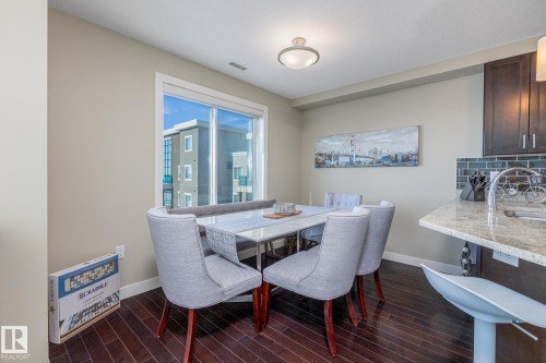 Dining area featuring dark wood-finish flooring, a large window, and recessed lighting - 513 1230 Windermere Way, Edmonton, AB 
