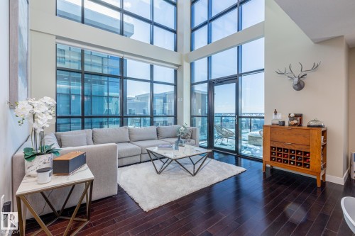 Double-height windows with dark framing and a glass door providing access to an outdoor area - 513 1230 Windermere Way, Edmonton, AB 