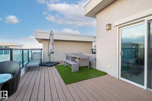 Modern multi-story building featuring multiple private balconies with glass railings, a large upper terrace, and expansive window walls - 513 1230 Windermere Way, Edmonton, AB 