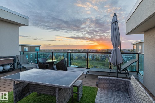 Multilevel exterior featuring a private balcony with blue-tinted glass railings, a full-height window wall, and multiple windows with white trim - 513 1230 Windermere Way, Edmonton, AB 