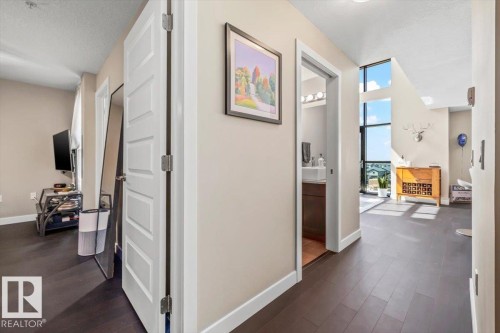 Two-story living area featuring dark wood-finish flooring, a wall of floor-to-ceiling windows, and a high ceiling - 513 1230 Windermere Way, Edmonton, AB 
