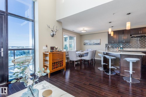 High ceilings and dark wood-finish flooring complement the open-concept living space - 513 1230 Windermere Way, Edmonton, AB 