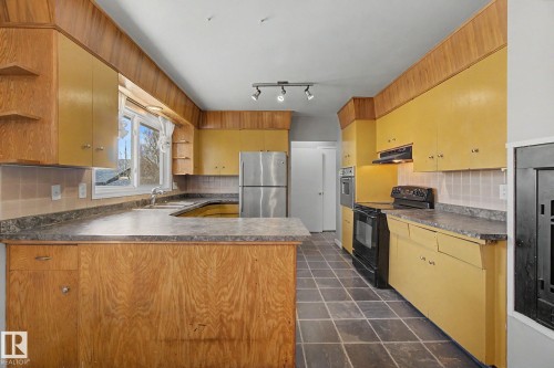 Kitchen featuring ample cabinetry, integrated oven, and a built-in range - 6048 105B Street, Edmonton, AB - Indoor Photo Showing Kitchen