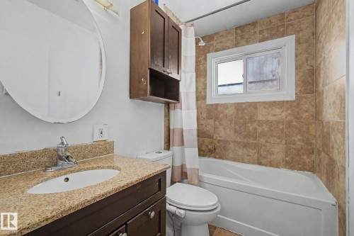 Bathroom featuring a granite-look vanity countertop, oval sink, and dark wood-finish cabinetry - 6048 105B Street, Edmonton, AB - Indoor Photo Showing Bathroom
