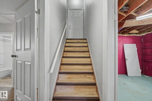 Staircase featuring wood-finish treads with contrasting risers, white handrail, and white paneled doors - 6048 105B Street, Edmonton, AB - Indoor Photo Showing Other Room