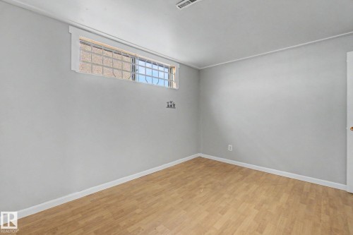Spacious room featuring light wood-finish flooring, neutral gray walls, and white baseboards - 6048 105B Street, Edmonton, AB - Indoor Photo Showing Other Room