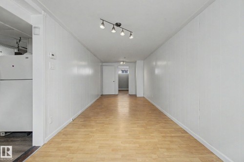Elongated interior space featuring light wood-finish flooring and track lighting - 6048 105B Street, Edmonton, AB - Indoor Photo Showing Other Room