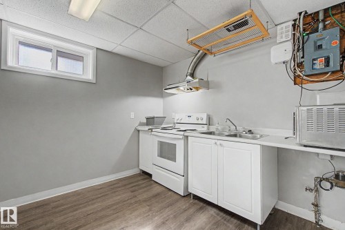 Kitchenette featuring white cabinetry, a double basin stainless steel sink, and a white electric range with an overhead exhaust hood - 6048 105B Street, Edmonton, AB - Indoor Photo Showing Kitchen With Double Sink