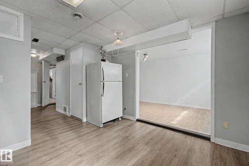 Spacious room featuring wood-finish flooring, light gray painted walls, and a drop ceiling - 6048 105B Street, Edmonton, AB - Indoor