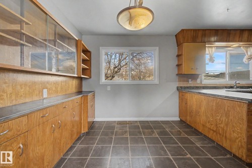 Kitchen featuring wood-finish cabinetry, a white rectangular sink, and tile flooring - 6048 105B Street, Edmonton, AB - Indoor Photo Showing Kitchen